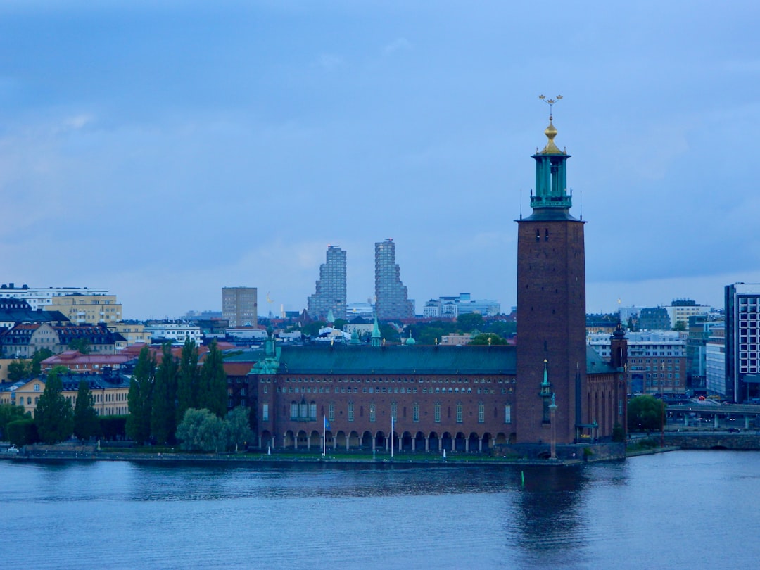 Brick building with a tall tower by the water.